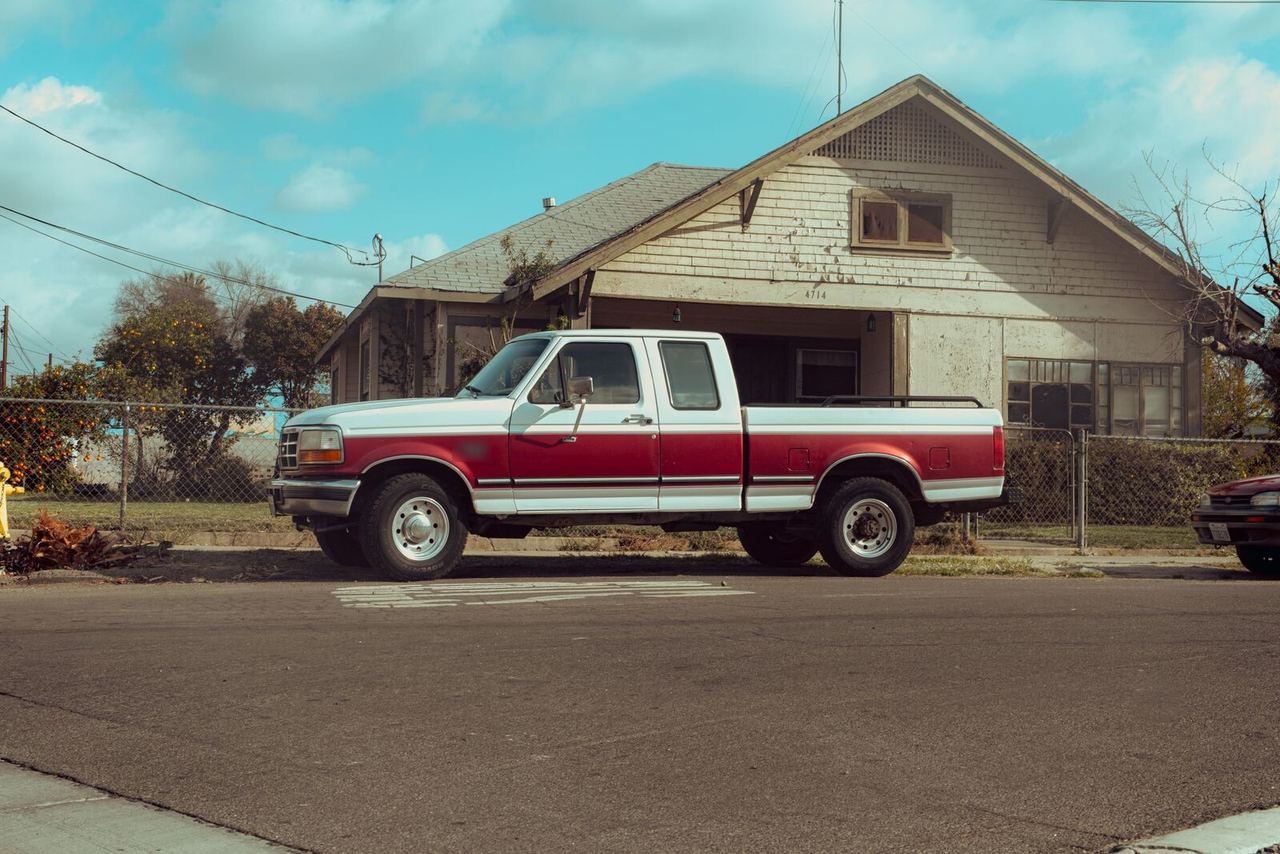 Camioneta pick-up roja y blanca frente a una casa